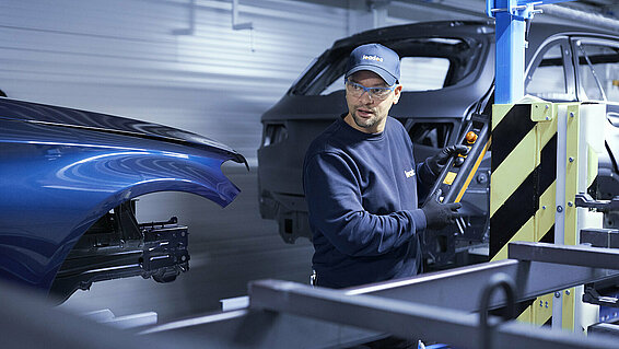 A Leadec employee troubleshooting the conveyor system in an automotive factory.