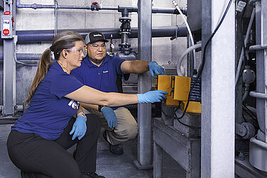 Zwei Leadec-Mitarbeitende bei der Überprüfung der Leistung einer Pumpe für Chemikalien.