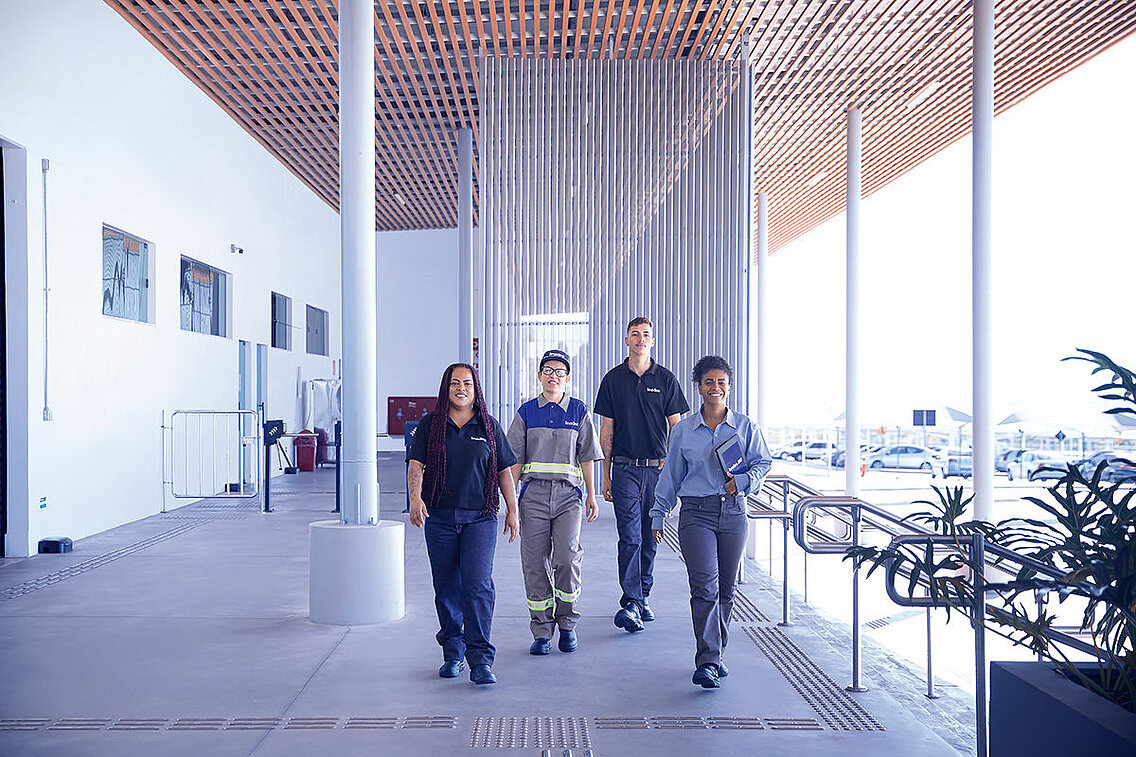 Four Leadec employees walking along a corridor inside a building.