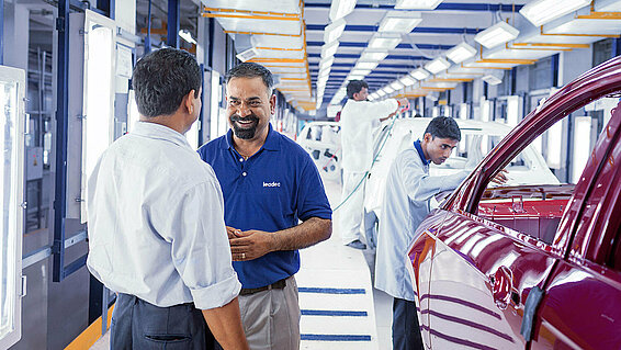 A Leadec employee talking to the customer in the paint shop of an automotive factory. 