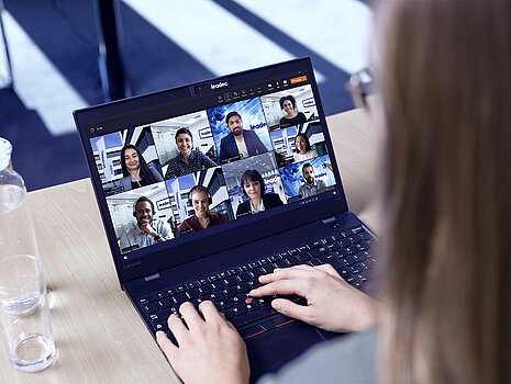 Ein Laptop, auf dem mehrere Kollegen bei einem virtuellen Meeting zu sehen sind.