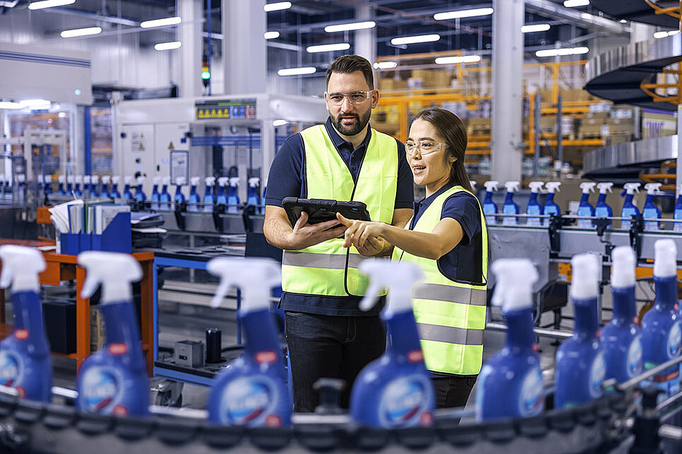 A male and a female Leadec employee looking at a tablet and monitoring the production of cleaning agents.