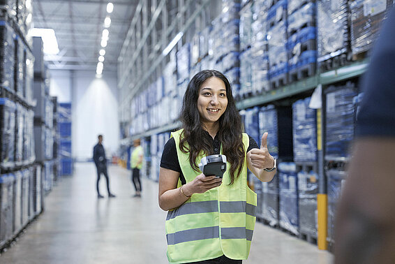 A female Leadec employee with safety vest and scanner giving a thumbs up.