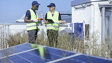 Zwei Leadec-Mitarbeiter auf einem Fabrikdach mit Photovoltaik-Modulen.