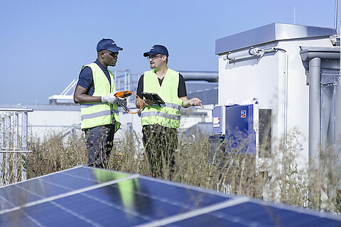 Zwei Leadec employees on factory roof with photovoltaic panels.