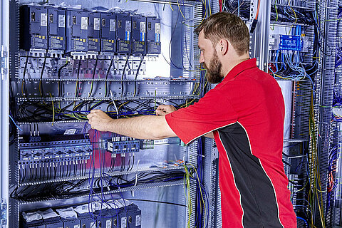 An employee carrying out electrical installation work on a switch cabinet. 