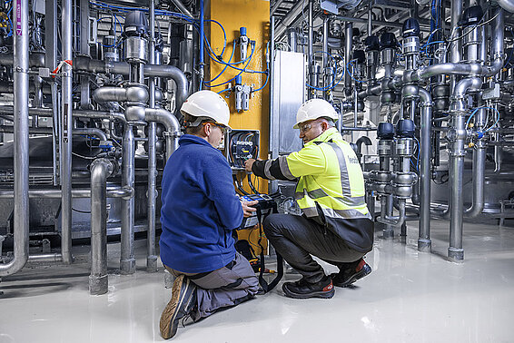 Two Leadec employees in a technical room inspecting the heat and ventilation system.