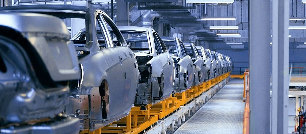 Car bodies on a conveyor belt in a factory.