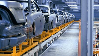 Car bodies on a conveyor belt in a factory.