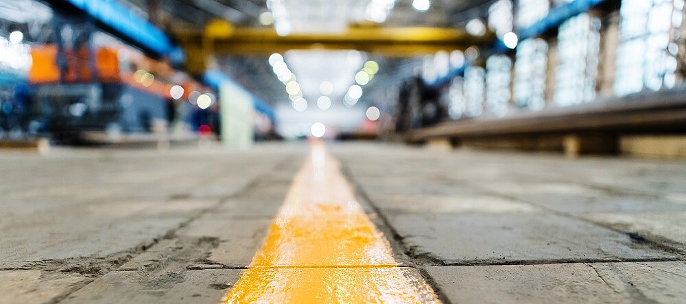 Eine breite gelbe Linie auf dem Boden einer Fabrik. 