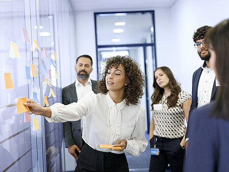 A group of Leadec employees in front of a wall with sticky notes at a workshop in the office.