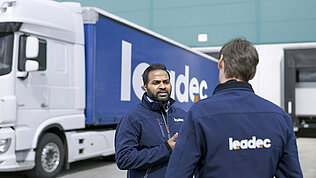 Two male Leadec employees talking in front of a truck.