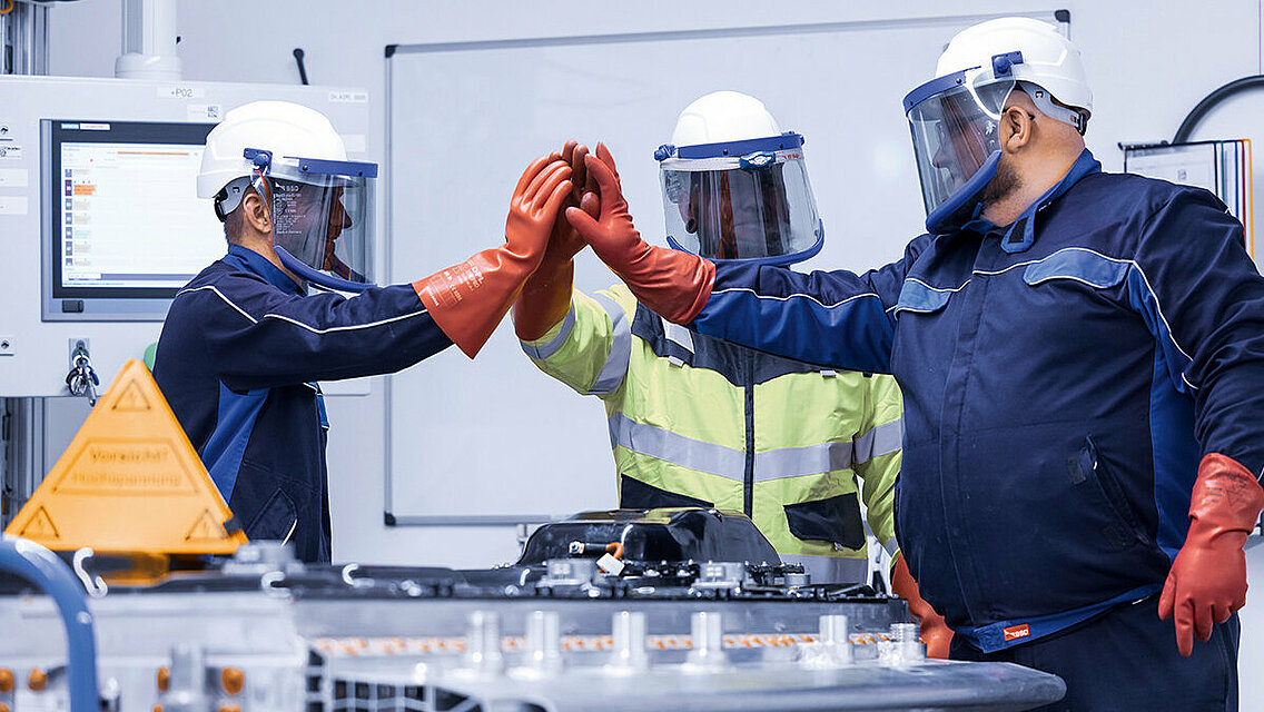 Leadec employees in protective giving high-five after successfully repairing a defective battery.
