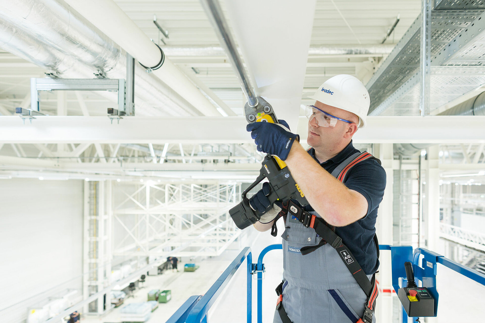Leadec-Mitarbeiter bei der Installation der Medienversorgung an der Decke einer Fabrik.