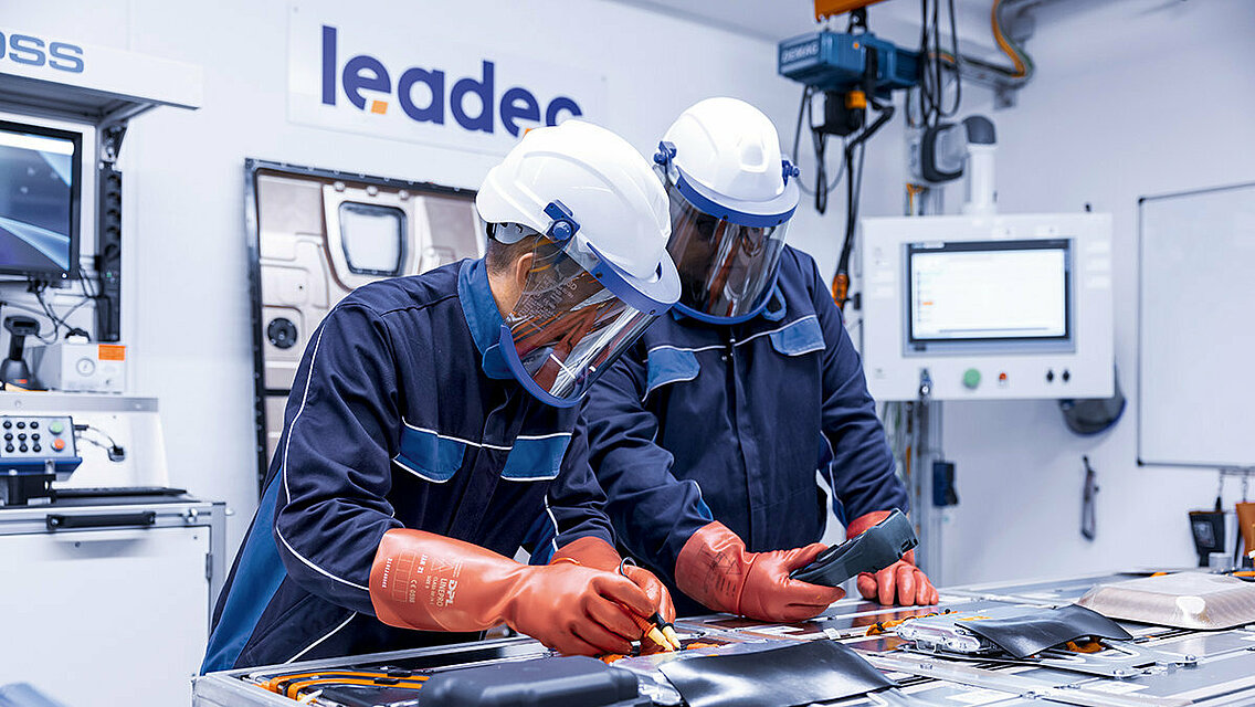 Two Leadec employees in protective clothing repairing a defective battery.