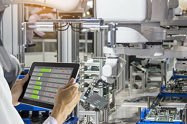 Employee with tablet in hand checks the performance of a machine.