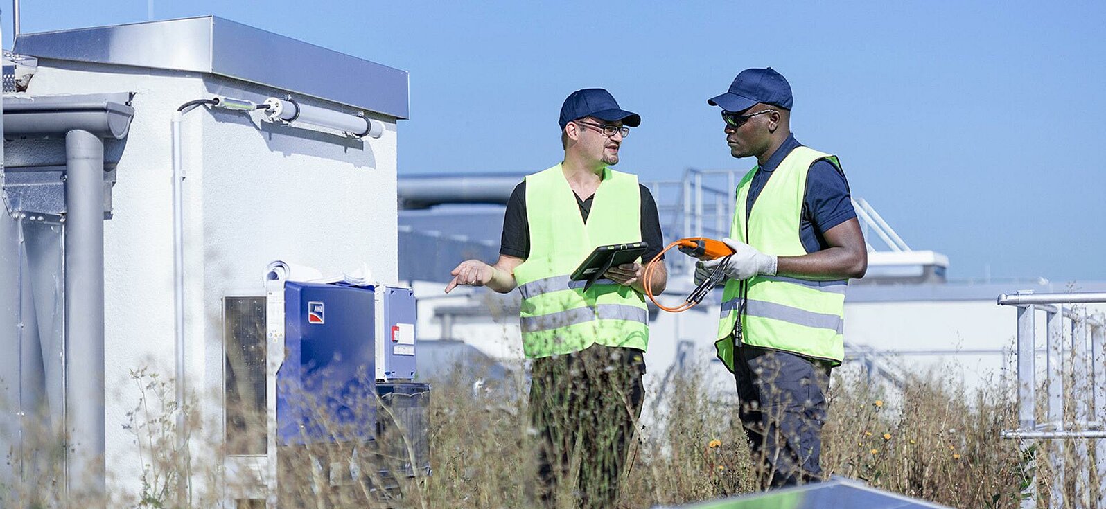 Zwei Leadec-Mitarbeiter auf einem Fabrikdach mit Photovoltaik-Modulen.