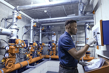 Leadec employee in technical room inspecting sprinkler system.