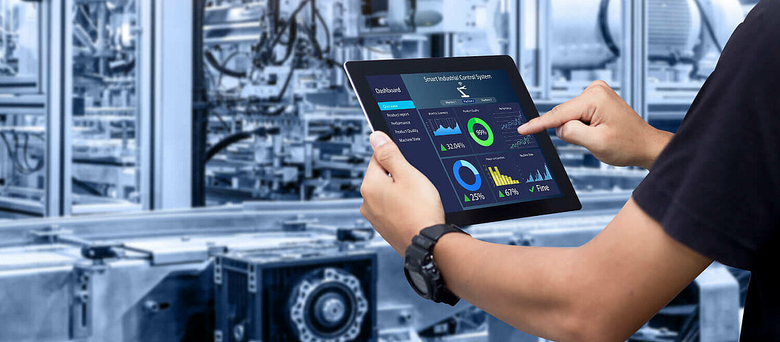 Employee with tablet in hand checks the performance of a machine.
