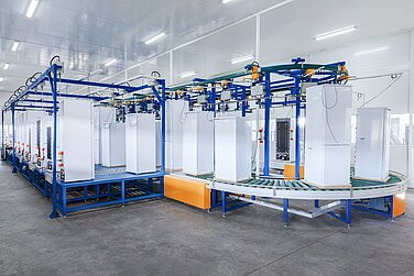 Ansicht eines Förderbands auf dem mehrere Kühlschränke stehen.
