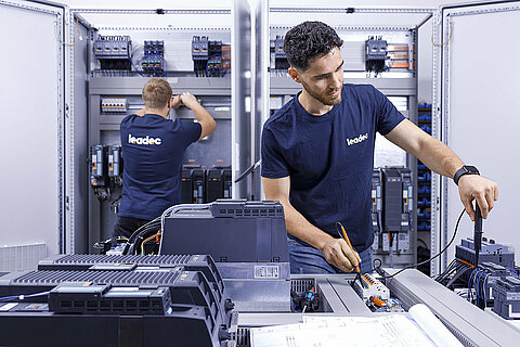 Two Leadec employees checking switch cabinets.