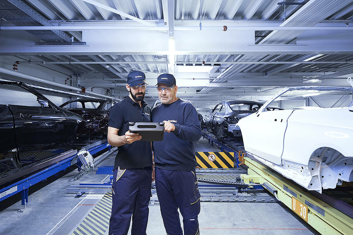 Two Leadec employees monitoring the automated conveyor technology using a tablet.