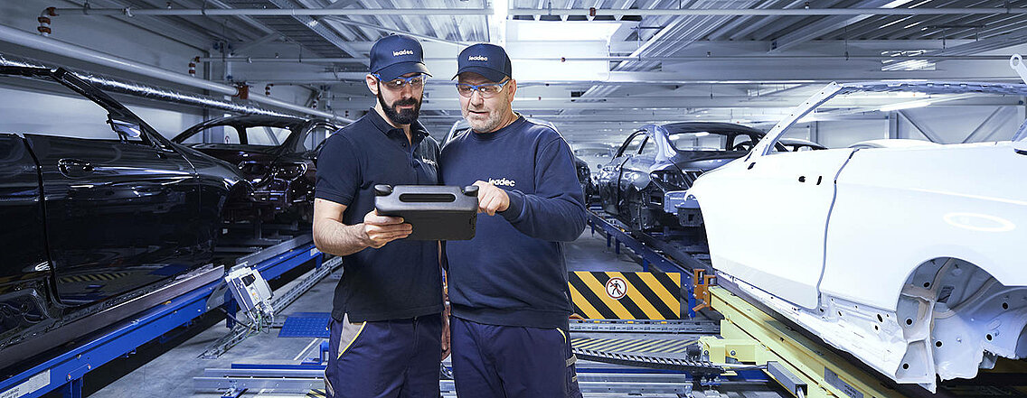 Zwei Leadec-Mitarbeiter überwachen die automatisierte Fördertechnik mit einem Tablet.