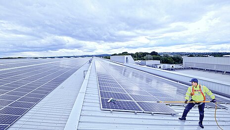 A Leadec employee cleaning the photovoltaic system on a factory roof.