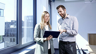 Two Leadec employees with a tablet in an office environment.