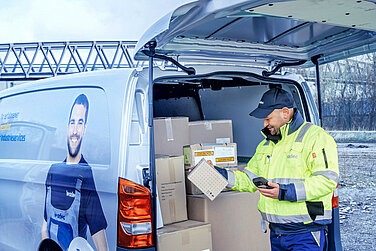 Man with scanner and a package in front of a van.