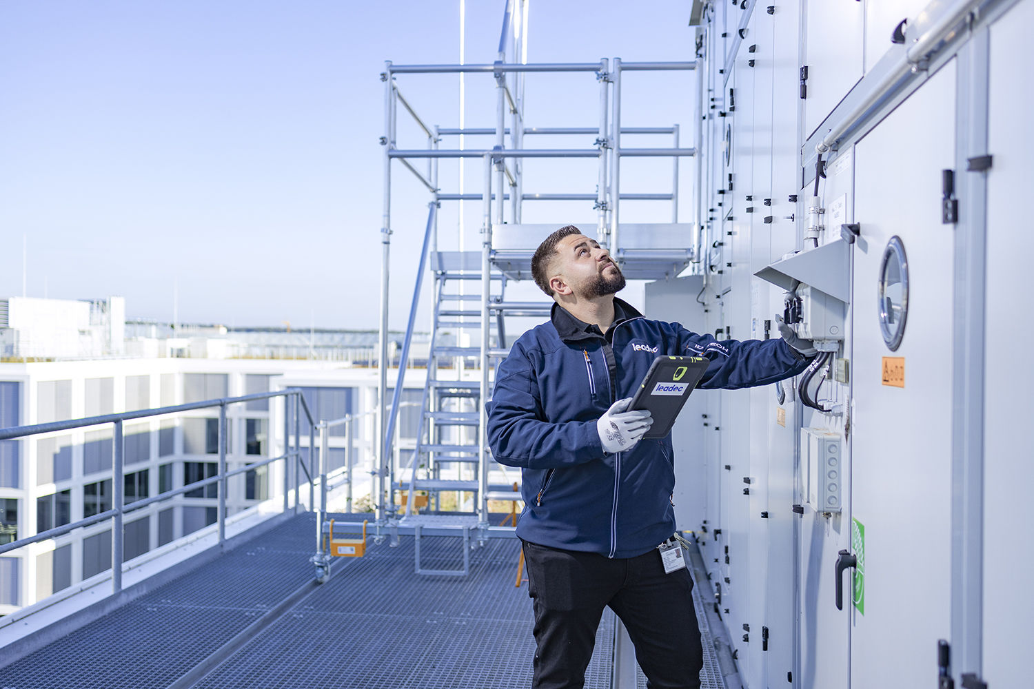 Leadec employee on a factory roof checks external installation of ventilation system.
