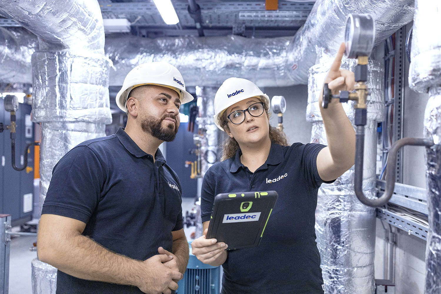 Two Leadec employees in front of a thermal power station