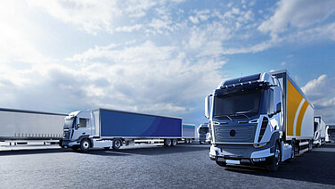 Several buses and trucks are parked together on an asphalt surface.