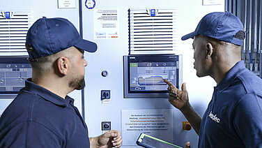 Leadec employees in front of screen of boiler plant.