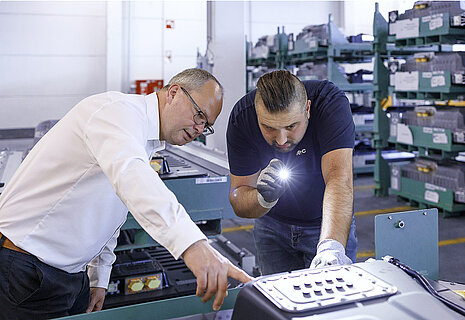 Two Leadec employees checking the battery on a housing.