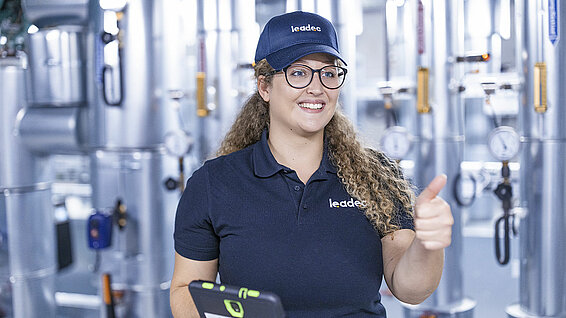 Female Leadec in a technical room employee hold thumbs up.
