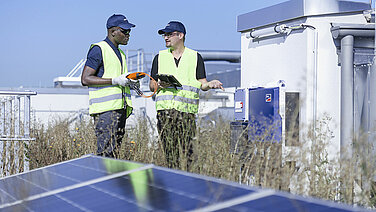 Two Leadec employees on factory roof with photovoltaic panels.