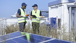 Two Leadec employees on factory roof with photovoltaic panels.