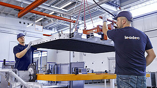 Two Leadec employees handling a battery housing.