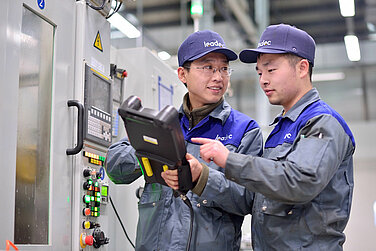 Zwei Leadec-Mitarbeiter mit Tablet in einer Fabrik.