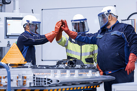 Leadec employees in protective giving high-five after successfully repairing a defective battery.