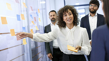 A group of Leadec employees in front of a wall with sticky notes at a workshop in the office.