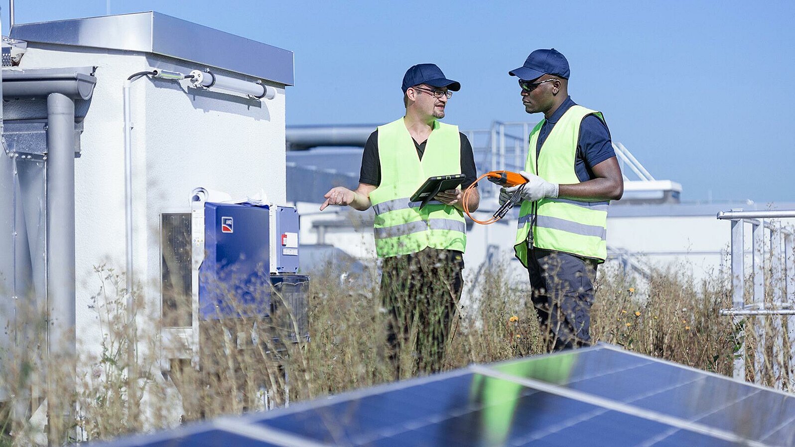 Zwei Leadec employees on factory roof with photovoltaic panels.