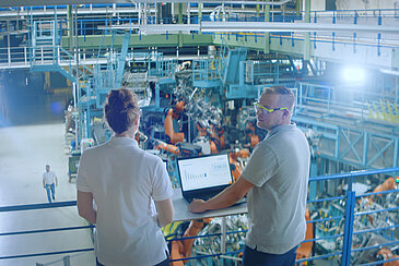 Two people with a laptop in a factory.