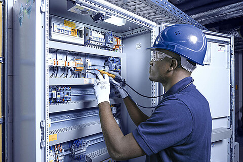 Leadec employee repairing control cabinet.