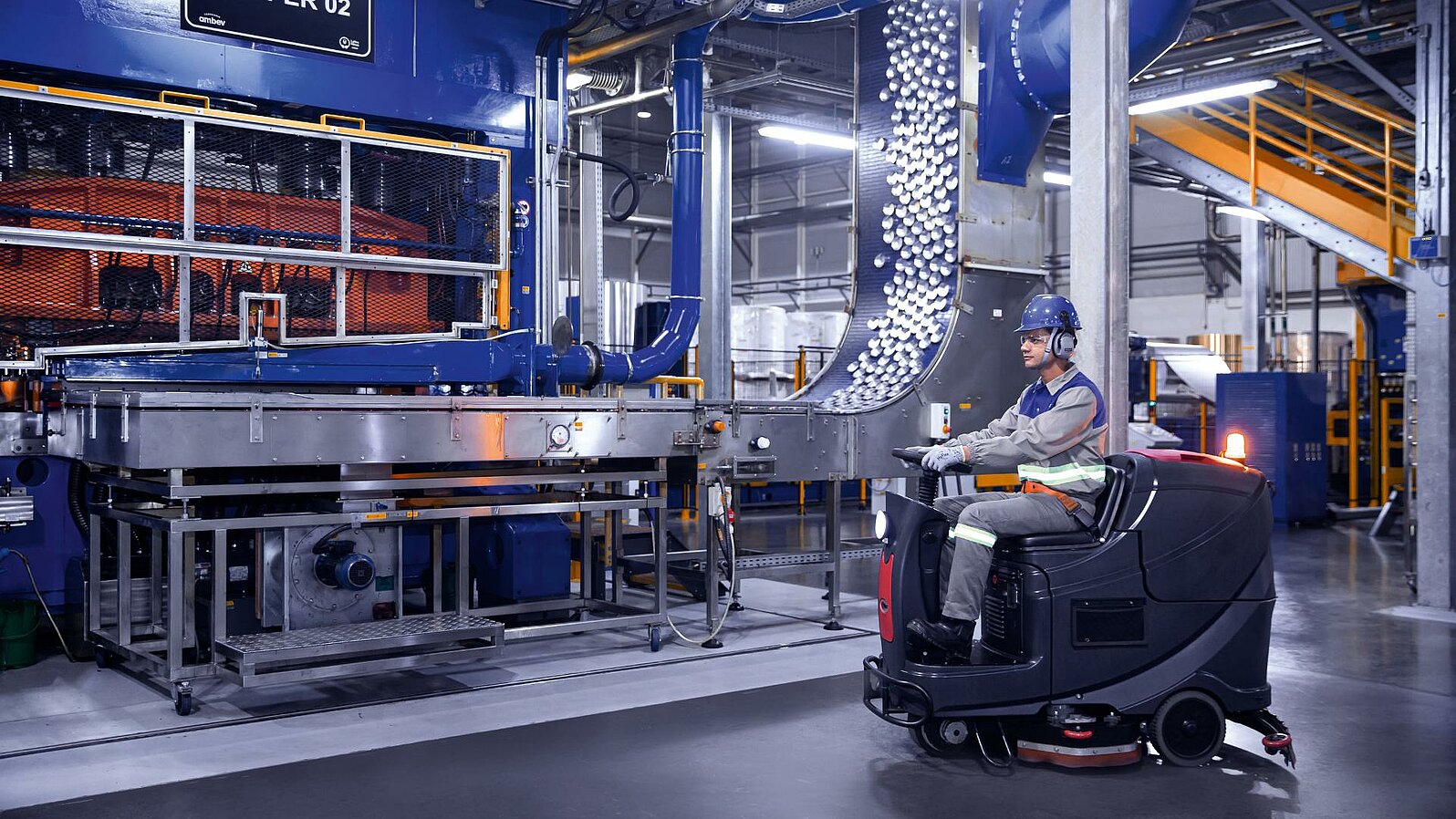 Leadec employee driving cleaning machine on shopfloor of Food & Beverage factory.